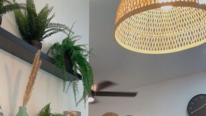Ett modernt vardagsrum med en tv, hyllor med växter, ett matbord med en bordsduk och en hängande lampa.