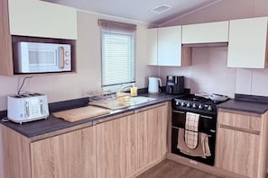 A compact kitchen with a microwave, toaster, coffee maker, and stove.