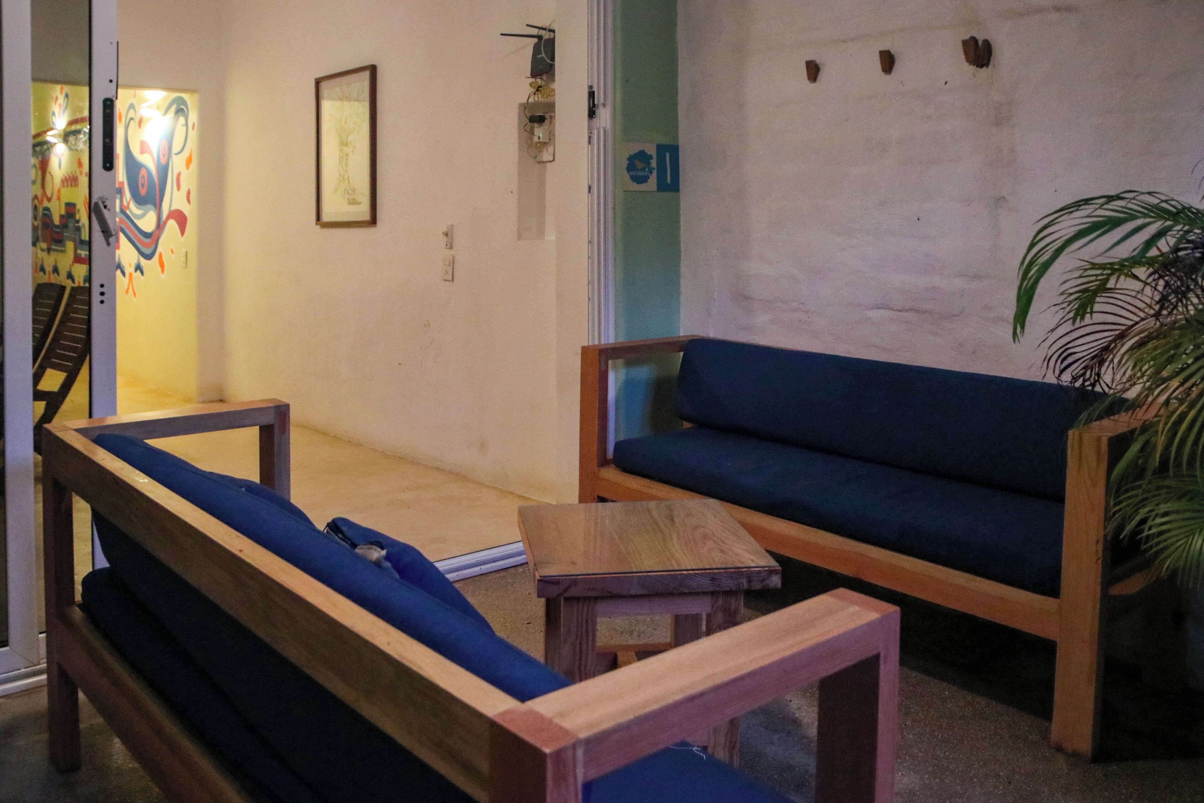 Quarto com um banco de madeira, um sofá azul e uma pequena mesa de madeira.