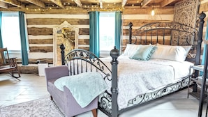 A log cabin bedroom with a bed, a rocking chair, and a patterned rug.