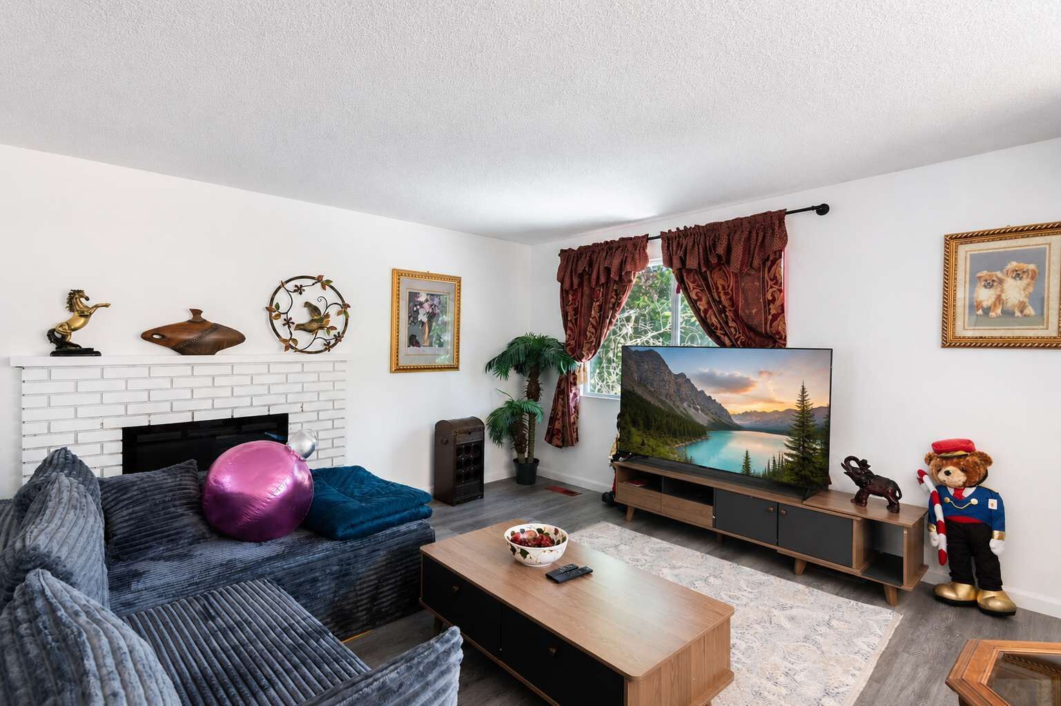 A living room with a fireplace, a television, a sofa, a coffee table, and decorative items.