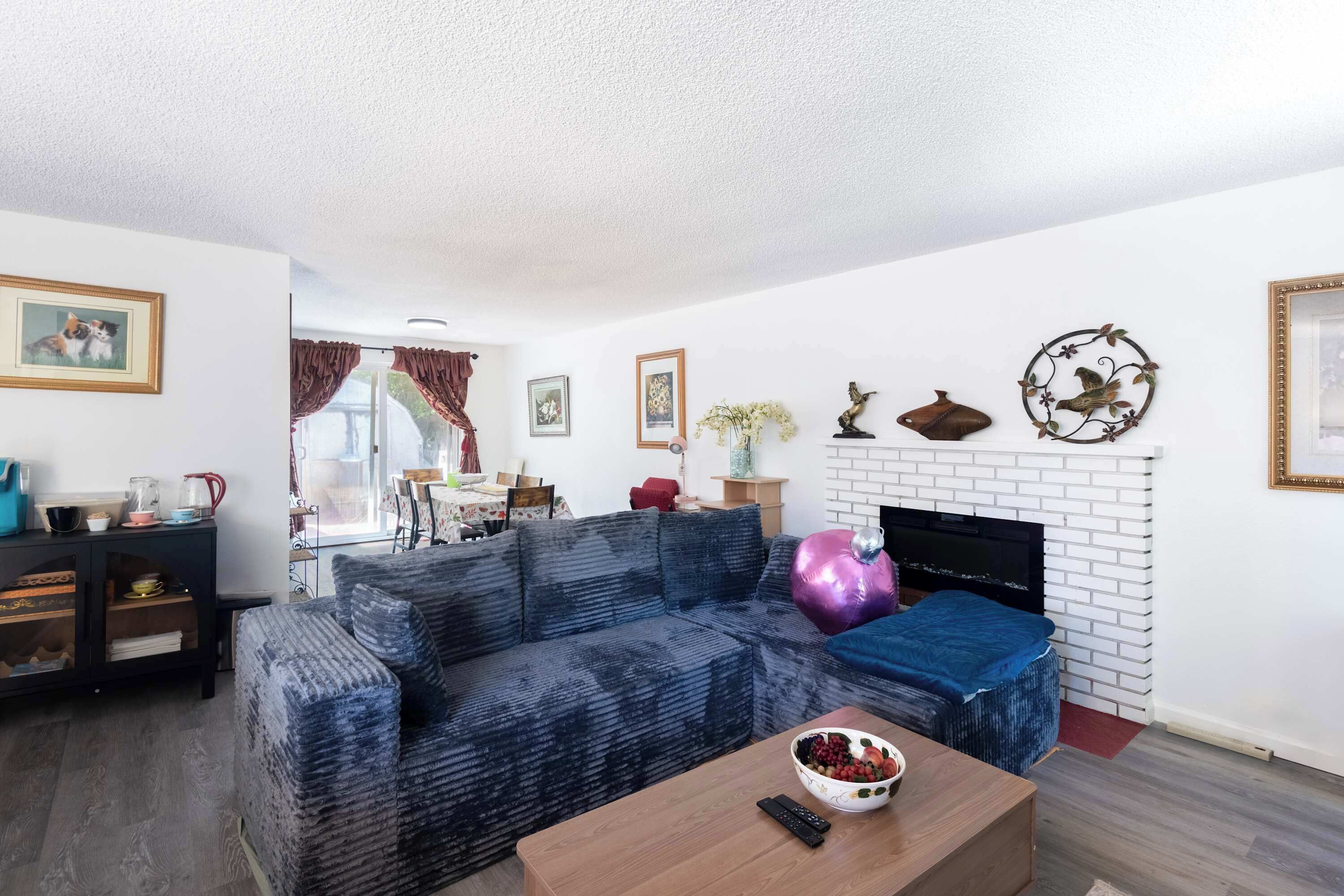 A living room with a sofa, a coffee table with a bowl of fruit, a fireplace, and wall decorations.