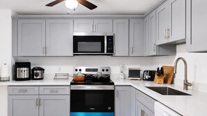 A modern kitchen with grey cabinets, a stainless steel microwave, a built-in oven, and a sink with a modern faucet. - Seattle Hillside Escape with Decks & Scenic Views (Seattle)