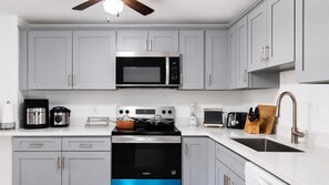 A modern kitchen with grey cabinets, a stainless steel microwave, a built-in oven, and a sink with a modern faucet. - Seattle Hillside Escape with Decks & Scenic Views (Seattle)