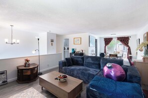 A living room with a sofa, coffee table, and a side table with a lamp. - Seattle Hillside Escape with Decks & Scenic Views (Seattle)