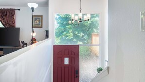 A staircase with a red door, a chandelier, a framed picture, and a television. - Seattle Hillside Escape with Decks & Scenic Views (Seattle)