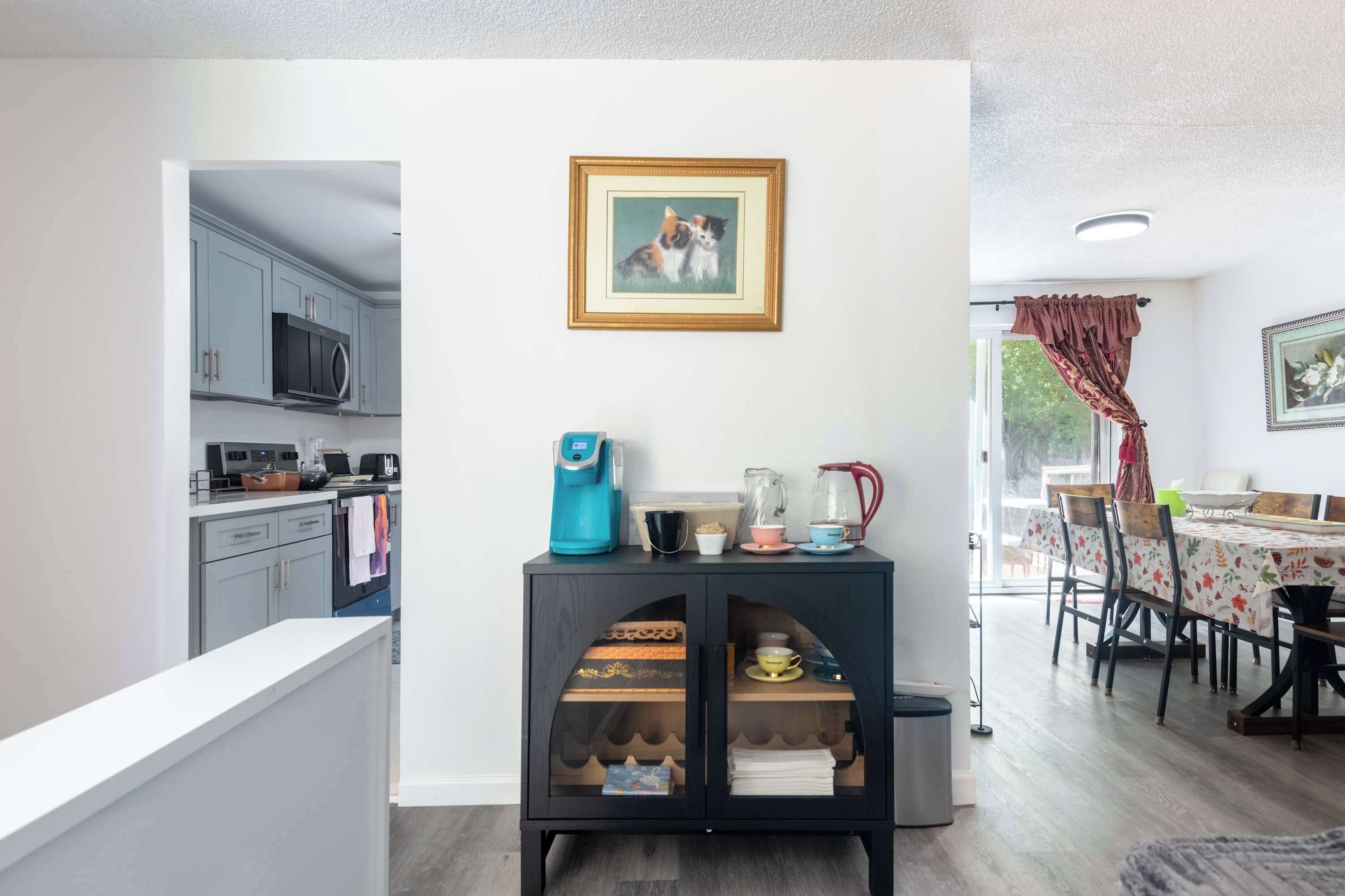 A modern kitchen with grey cabinets, a microwave, and a coffee maker on a black cabinet.