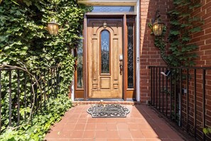 A brick building with a wooden door, a welcome mat, and two wall-mounted lanterns. - Mableton 4BR - Near Truist Park & Six Flags (Mableton)