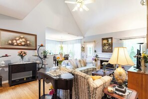 A living room with a sofa, a dining table, a fireplace, and a ceiling fan. - Mableton 4BR - Near Truist Park & Six Flags (Mableton)