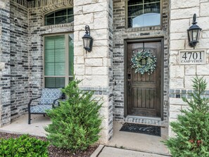 A stone building with a wooden door, a bench, and a wreath on the door.