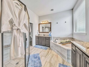 Une salle de bain moderne dotée d’une douche à parois de verre, d’un meuble-lavabo et d’un grand miroir avec éclairage intégré.