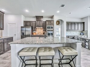 A modern kitchen with granite countertops, stainless steel appliances, and a central island with bar stools.