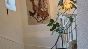 Eine Treppe mit einem Gemälde von Pferden, einer Pflanze und einem weißen Geländer.