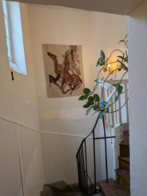 A staircase with a painting of horses, a plant, and a white railing. - The Gates of Baudet (MIREFLEURS)