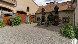 Ein Innenhof mit Steingebäuden, Holztüren und einem Kiesweg.