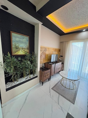 A modern living room with a painting, plants, a TV, and a dining area. - PERLA SUİTES (İstanbul)