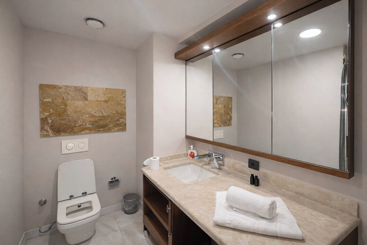 Uma casa de banho moderna com sanita, lavatório e espelho.
