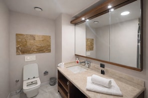 A modern bathroom with a toilet, sink, and mirror. - PERLA SUİTES (İstanbul)