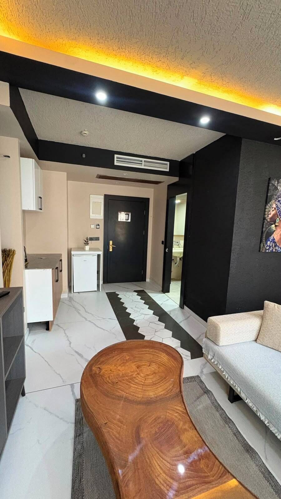 A modern living room with a sofa, a coffee table, and a kitchen area in the background.