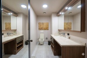 Uma casa de banho moderna com duas lavatórios, uma sanita e um espelho grande.