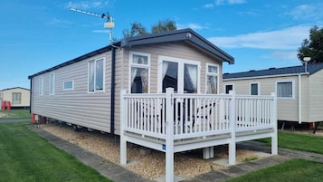 A mobile home with a deck, a satellite dish, and a number 469 sign.