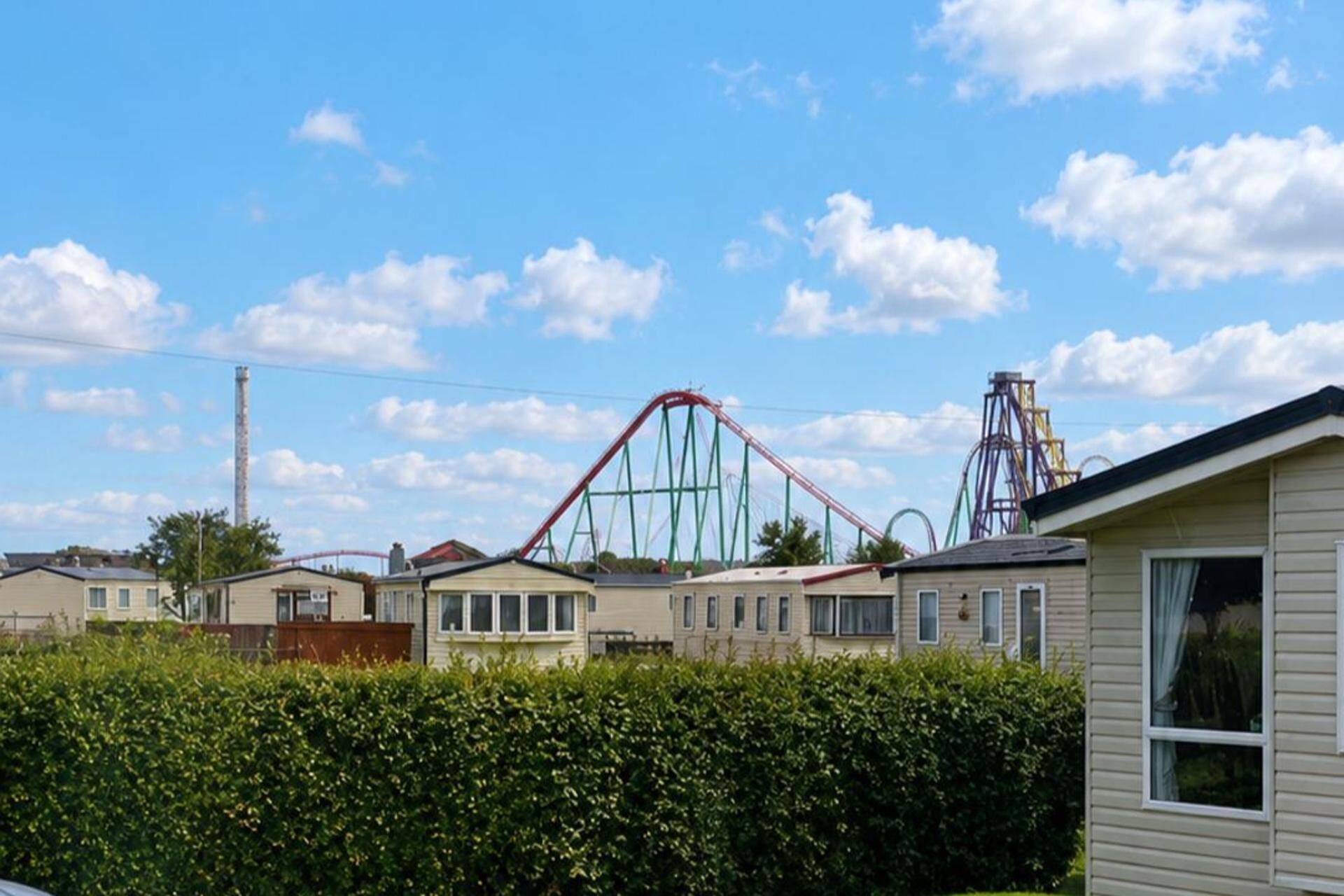 A row of single-story houses with a roller coaster in the background.