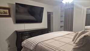 A bedroom with a bed, a dresser, a television, and a closet.