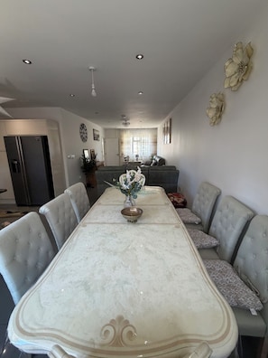 Comedor con una mesa de mármol, sillas tapizadas en gris y un jarrón con flores.