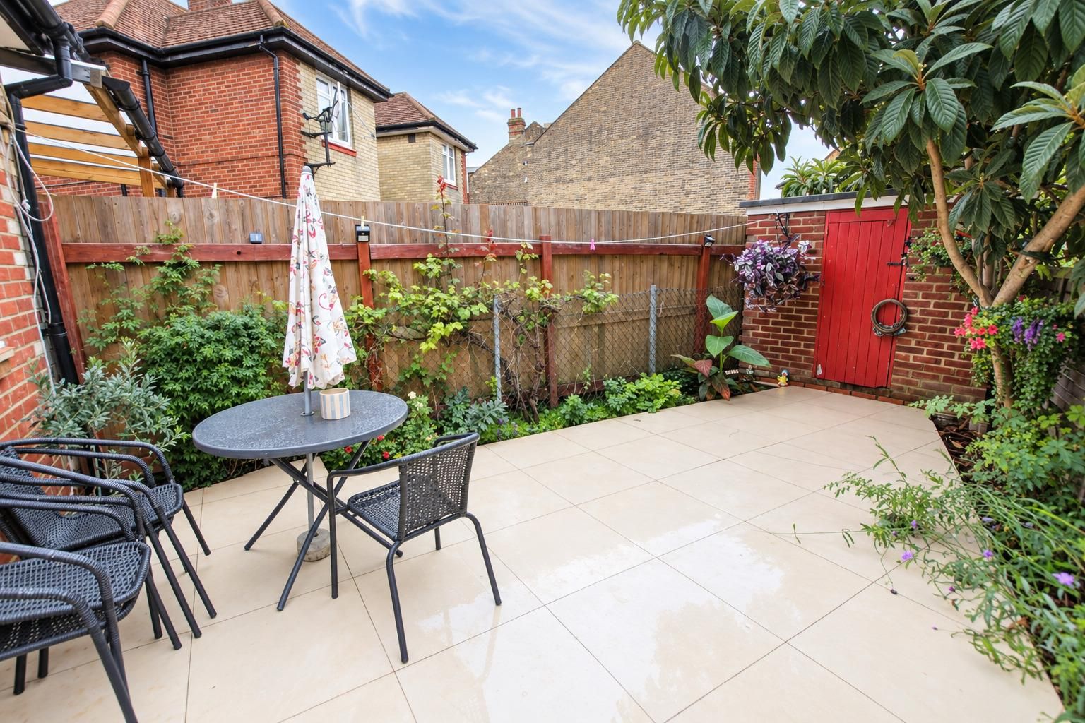 A patio with a round table and chairs, surrounded by a brick wall and a wooden fence.