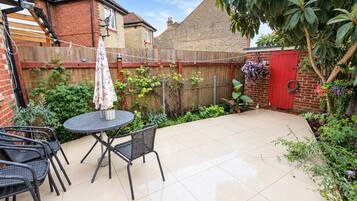 A patio with a round table and chairs, surrounded by a brick wall and a wooden fence.