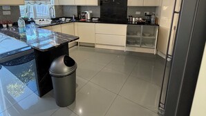 A modern kitchen with a central island, white cabinets, a black refrigerator, and a decorative light fixture. - Greenview Manor house in Tottenham North London 4BRM 2bath (London)