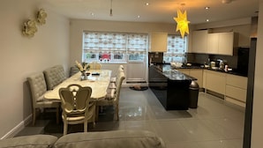 A modern kitchen with a dining area, featuring a central island, recessed lighting, and a decorative star-shaped light fixture. - Greenview Manor house in Tottenham North London 4BRM 2bath (London)
