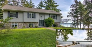 Une maison à deux étages, avec des fondations en pierre, un porche à l’avant et une vue sur un lac.