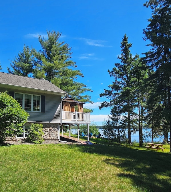 A house with a porch, a stone foundation, and a view of a lake.