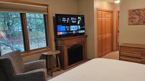 Ein Schlafzimmer mit Fernseher, Kamin, Holzkommode, Stuhl und einer Karte an der Wand.