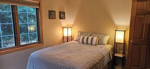 Una camera da letto con un letto, due lampade ai comodini, una finestra e due cartelli fissati al muro.