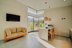 Un interior moderno con sofá, mesa de comedor y ventanas amplias que ofrecen vistas a zonas verdes.