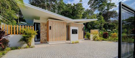 Une villa moderne avec un mur en pierre, des lambris en bois et une enseigne indiquant « Tsuru Villas ».