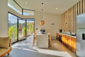Una cocina moderna con una isla central, ventanas amplias y vistas a zonas verdes.