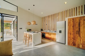 A modern kitchen with a central island, wooden accents, and pendant lighting. - Villas Tsuru (Hone Creek)