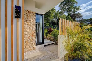 A modern building with a stone facade, a glass door, and a wooden fence.