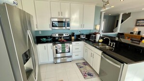 A modern kitchen with white cabinets, stainless steel appliances, and a black countertop. - Big Waterfront House! Fishing Dock, Arcade, Garage Parking, Walk to Beach! (Norfolk)