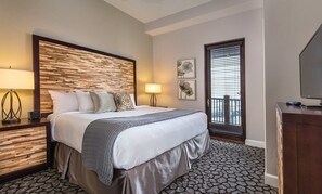 Een hotelkamer met een bed, bedlampen, een dressoir, een televisie en een raam met jaloezieën.