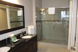Een moderne badkamer met een douchecabine van glas, een grote spiegel en een wastafelmeubel met een wastafel en toiletartikelen.