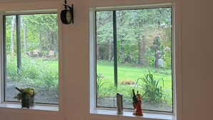 Una habitación con dos ventanas grandes, un reloj de pared y un radiador.