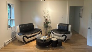 Una sala de estar moderna con dos sofás de cuero negro, una mesa de centro de cristal y una planta decorativa.