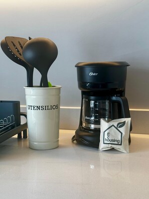 Eine Küchenzeile mit Kaffeemaschine, Geschirr und einer Kaffeepackung.