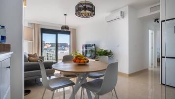 A modern kitchen with a dining table, chairs, and a fruit bowl.