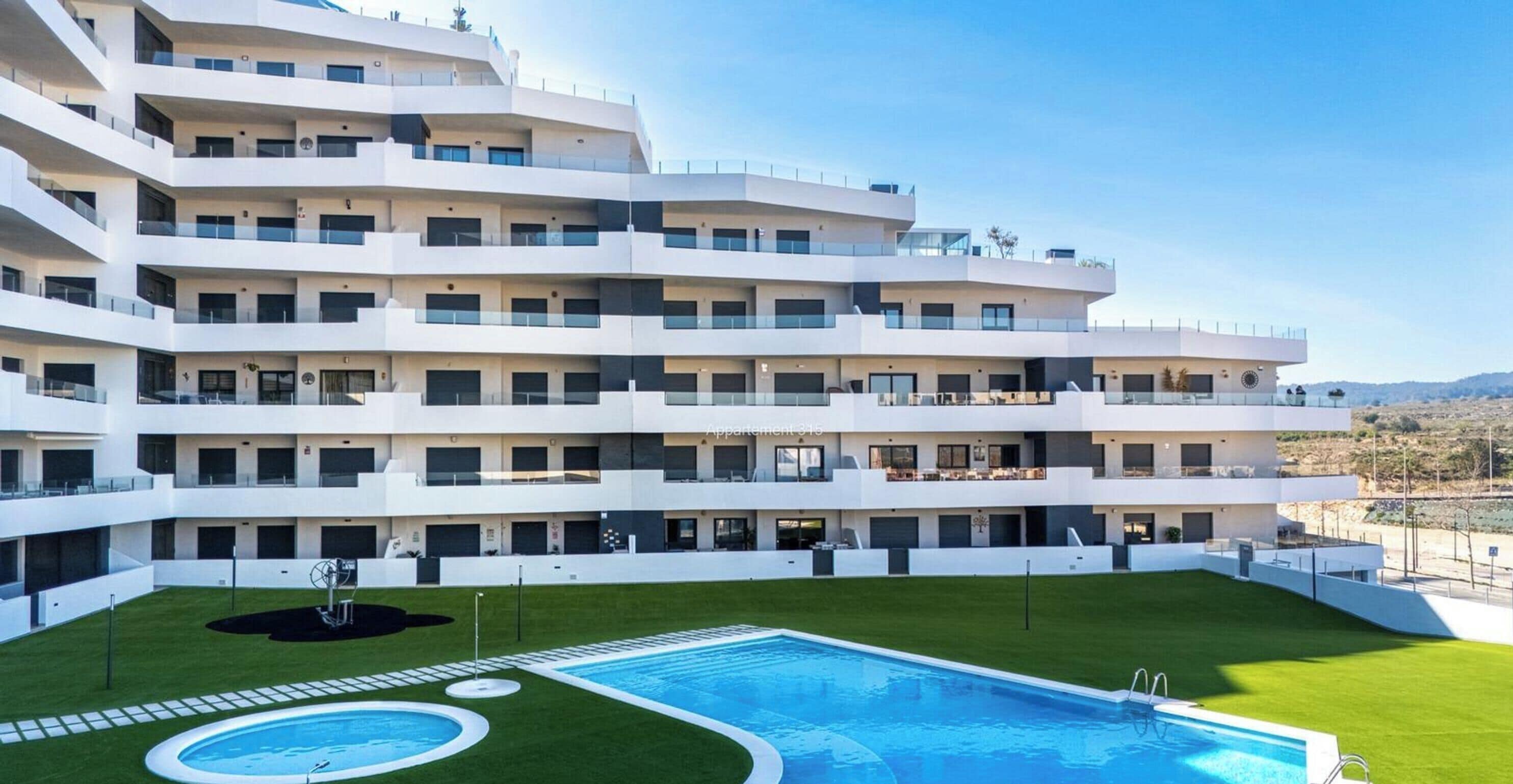 A multi-story hotel with a swimming pool and a landscaped lawn.
