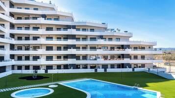 A multi-story hotel with a swimming pool and a landscaped lawn.